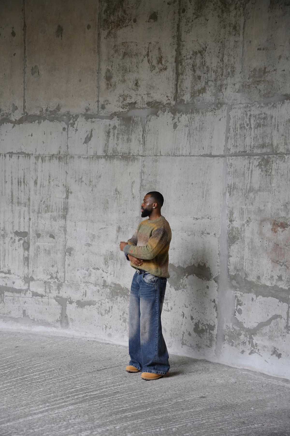 Editorial portrait of a person standing against a concrete wall, used as an anonymous campaign concept