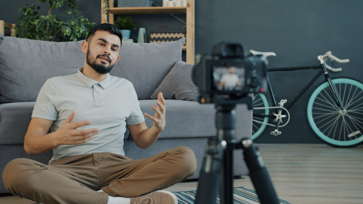 Creator sitting on the floor speaking to a camera on a tripod