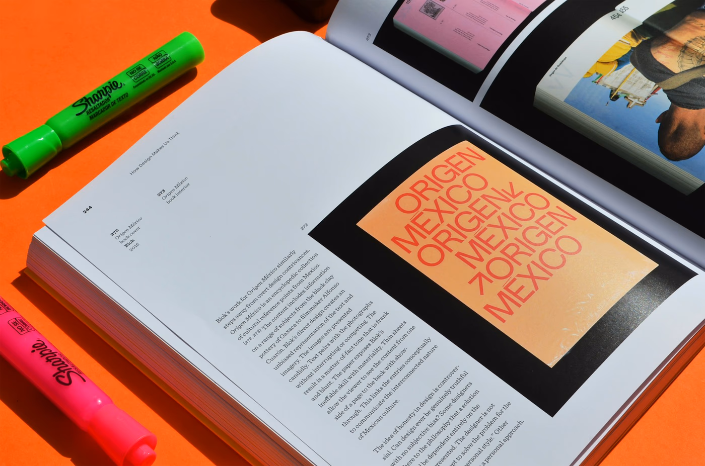 Open editorial book with orange pages and paper markers