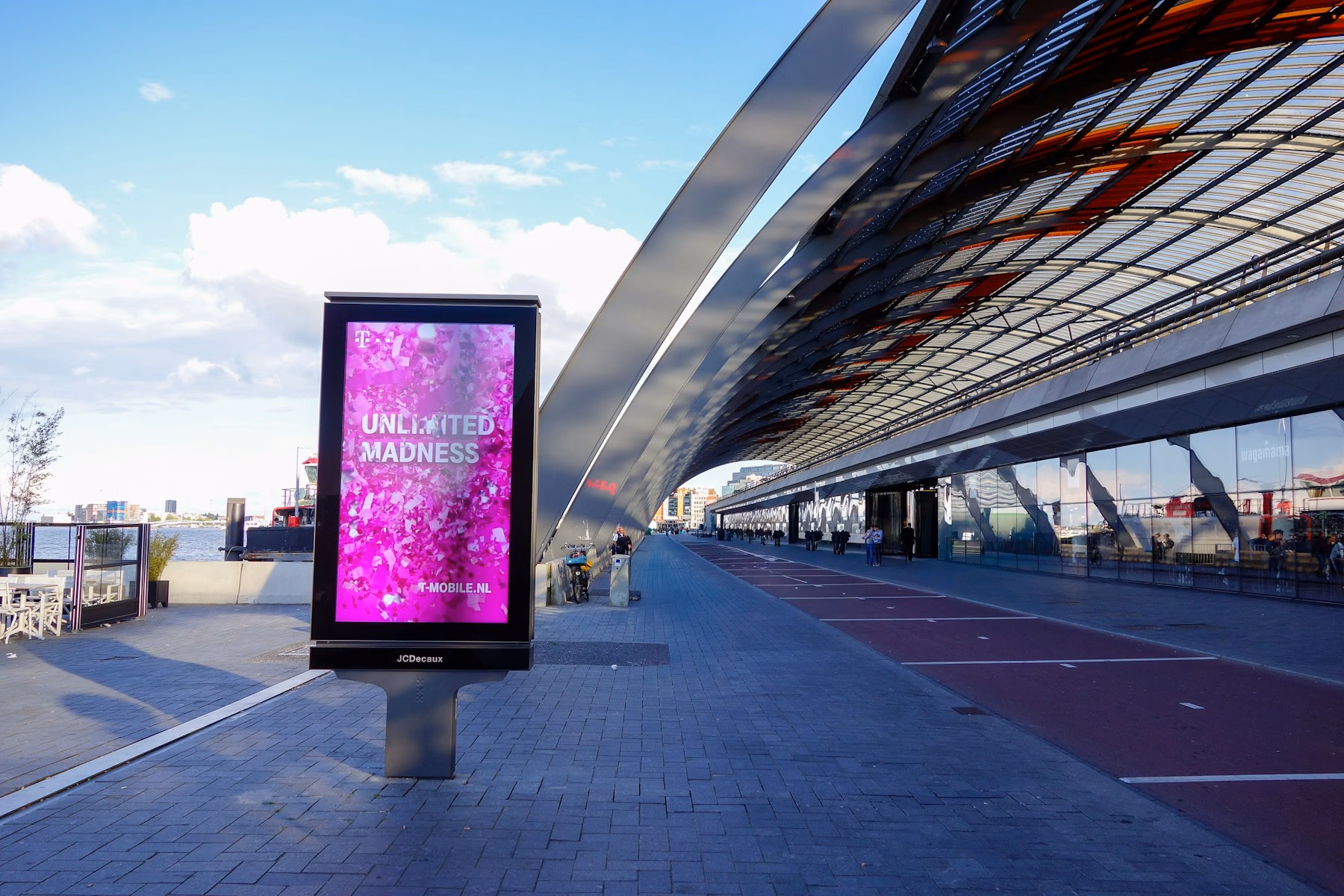 Outdoor digital billboard showing pink abstract art in an architectural setting
